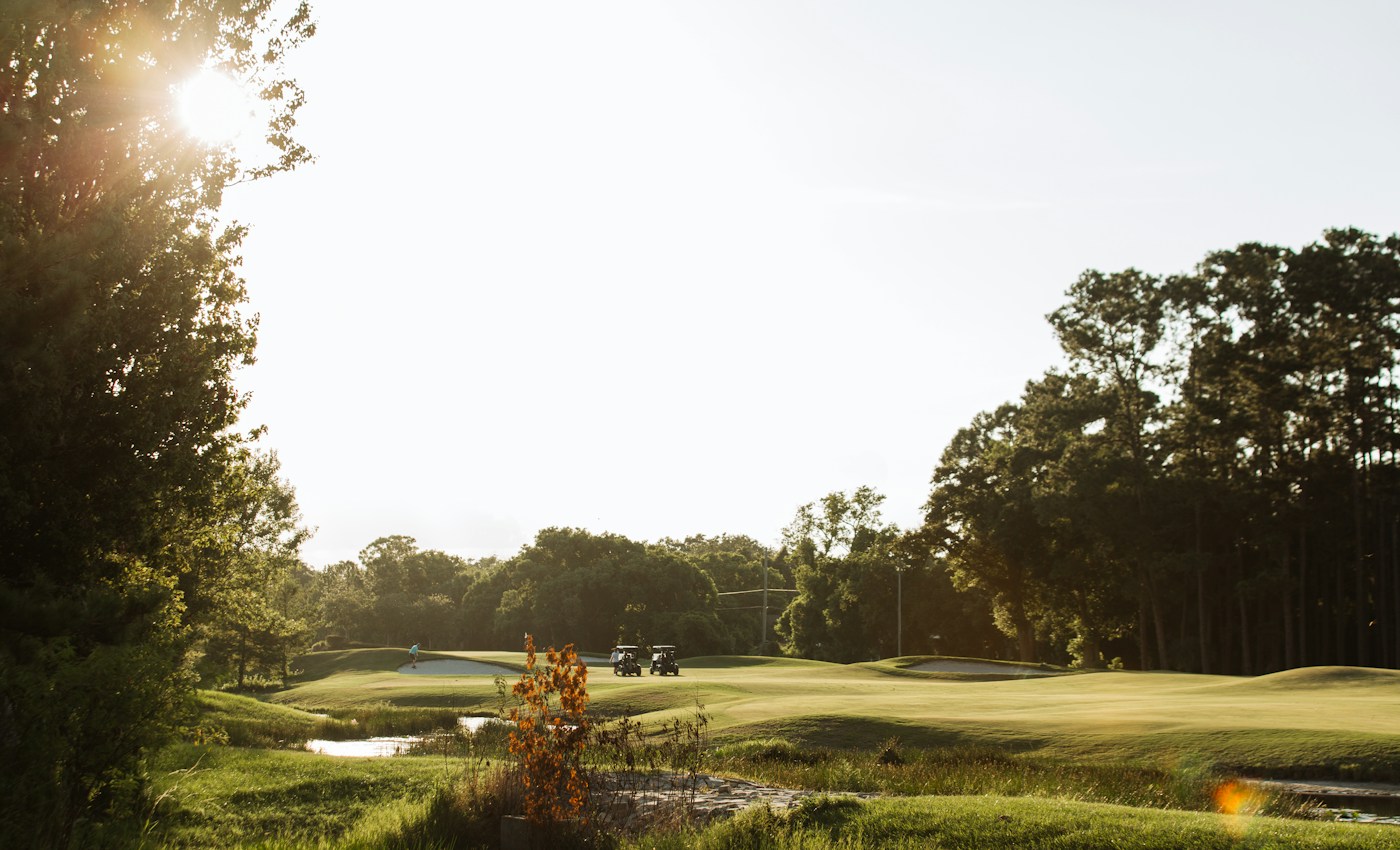 A sunlit golf course surrounded by trees